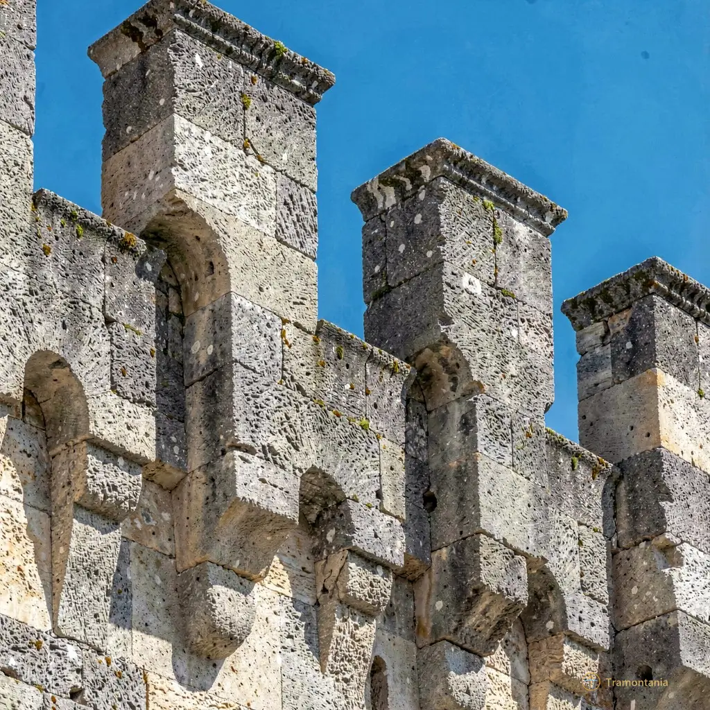 Détail architectural des créneaux du château montrant la texture rugueuse de la pierre face au ciel bleu azur